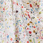 Draped fabric yardage in a playful illustrated "stuff" print in multicolor pastels on a white field.