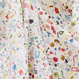 Draped fabric yardage in a playful illustrated "stuff" print in multicolor pastels on a white field.