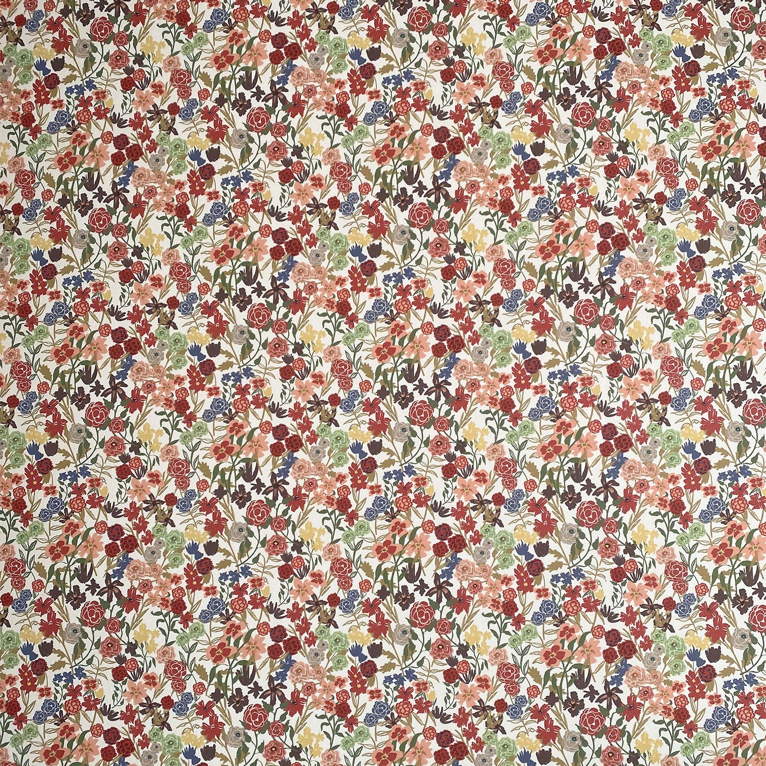 Detail of wallpaper in a dense small-scale floral print in shades of coral, red, green and blue on a white field.