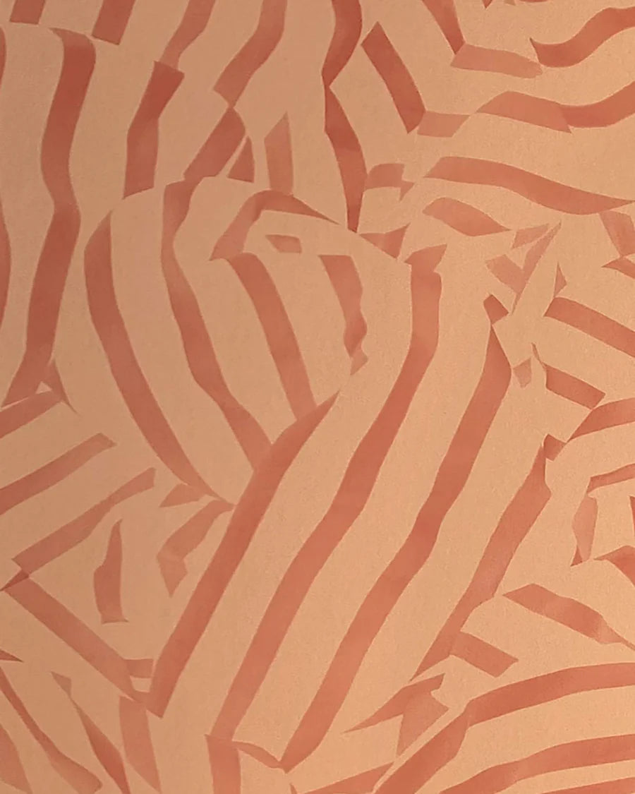 Detail of wallpaper in a playful broken stripe print in rust on an orange field.