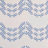 Detail of wallpaper in a curving floral stripe print in shades of blue on a cream field.