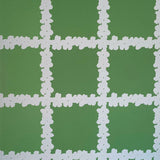 Detail of wallpaper in a floral grid print in white on a green field.