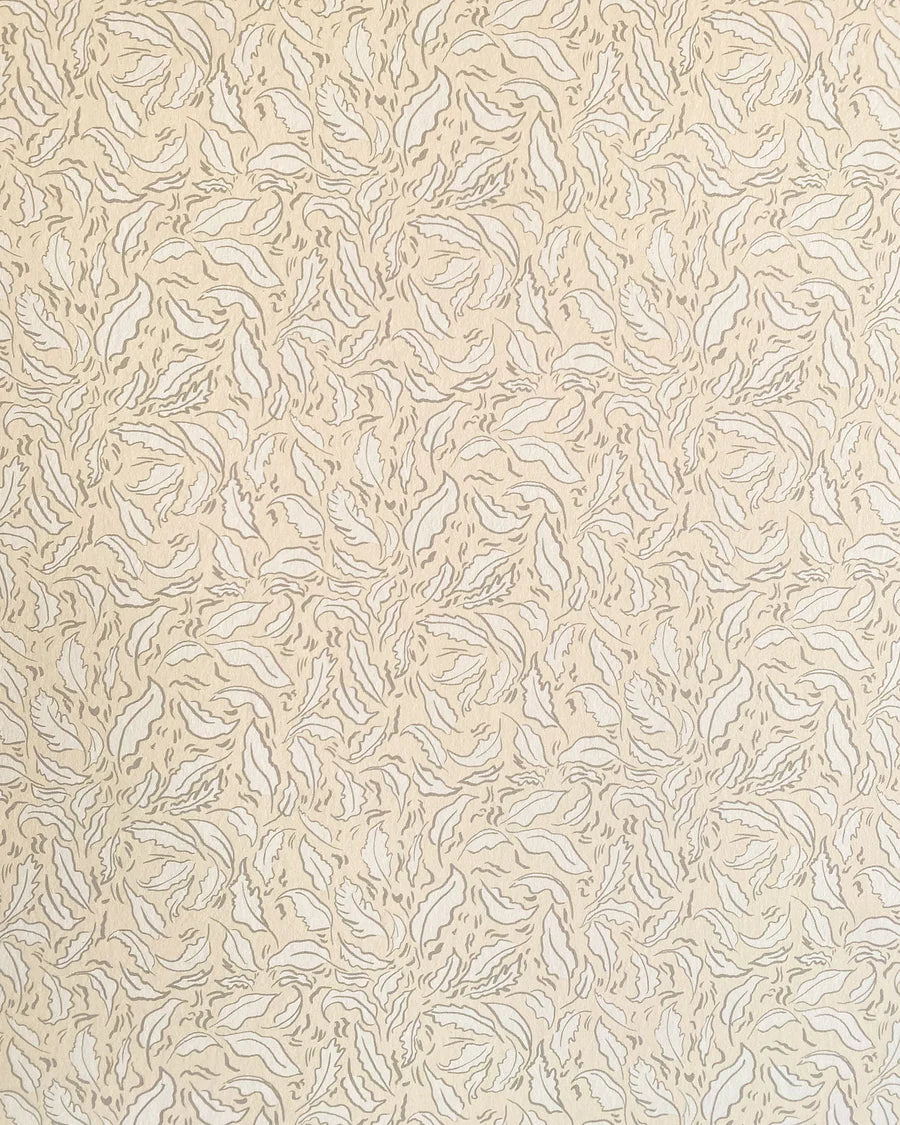 Detail of wallpaper in a painterly leaf print in tan and white on a cream field.