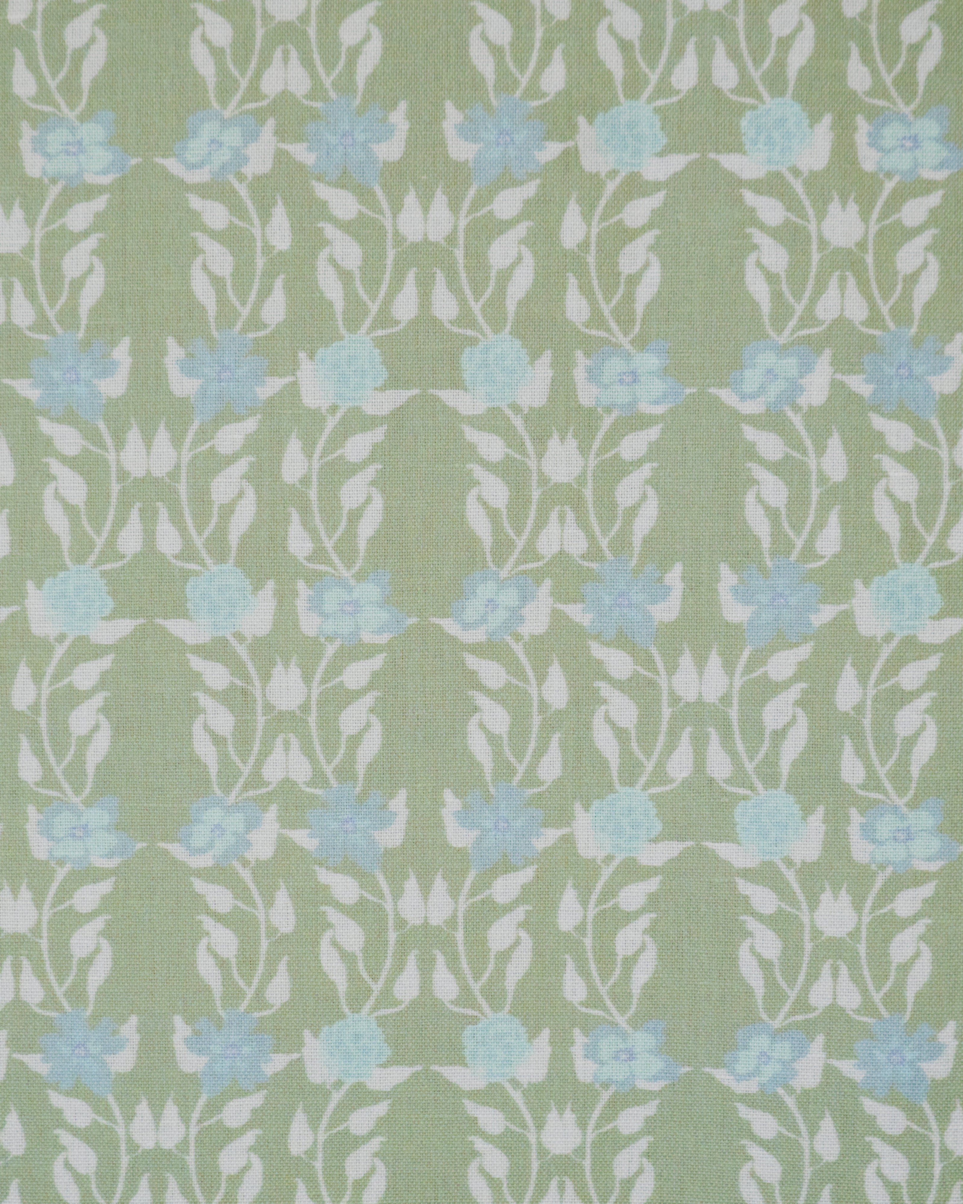 Detail of fabric in a linear floral print in blue and white on a green field.