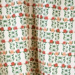 Draped fabric yardage in a linear floral print in red, orange and green on a white field.