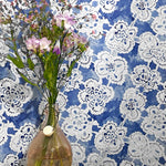Vase with flowers against a blue wall with white lace patterns