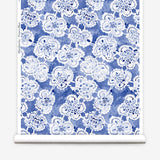 Wallpaper roll with blue watercolor lace floral pattern on a white background.