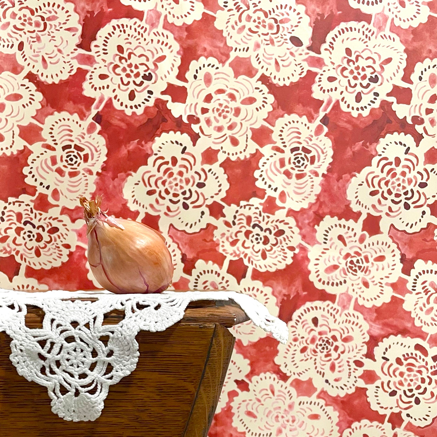 Doily with a red floral pattern on a wooden surface