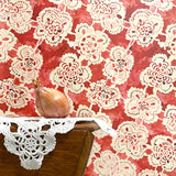 Doily with a red floral pattern on a wooden surface
