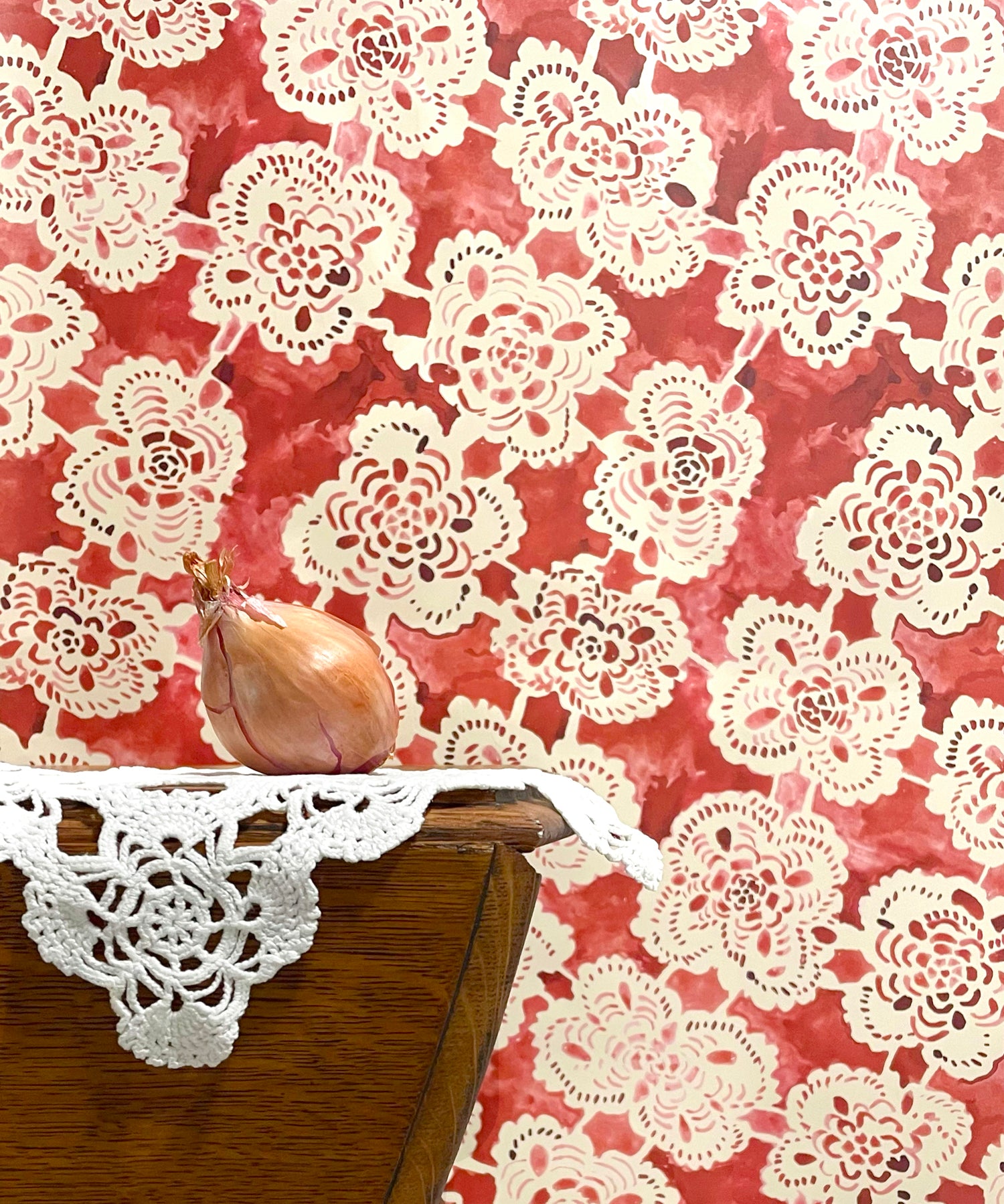 Doily with a red floral pattern on a wooden surface