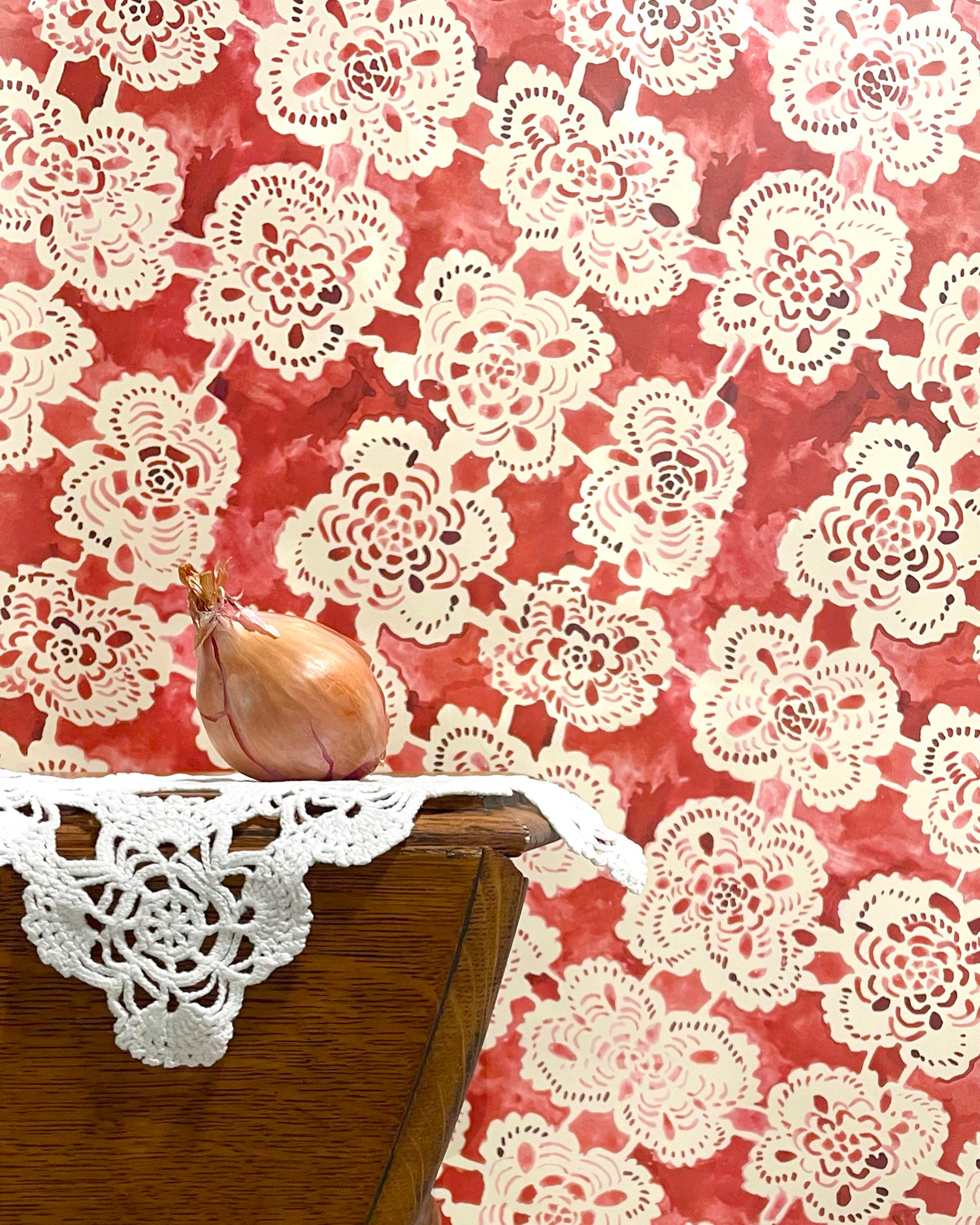 Doily with a red floral pattern on a wooden surface