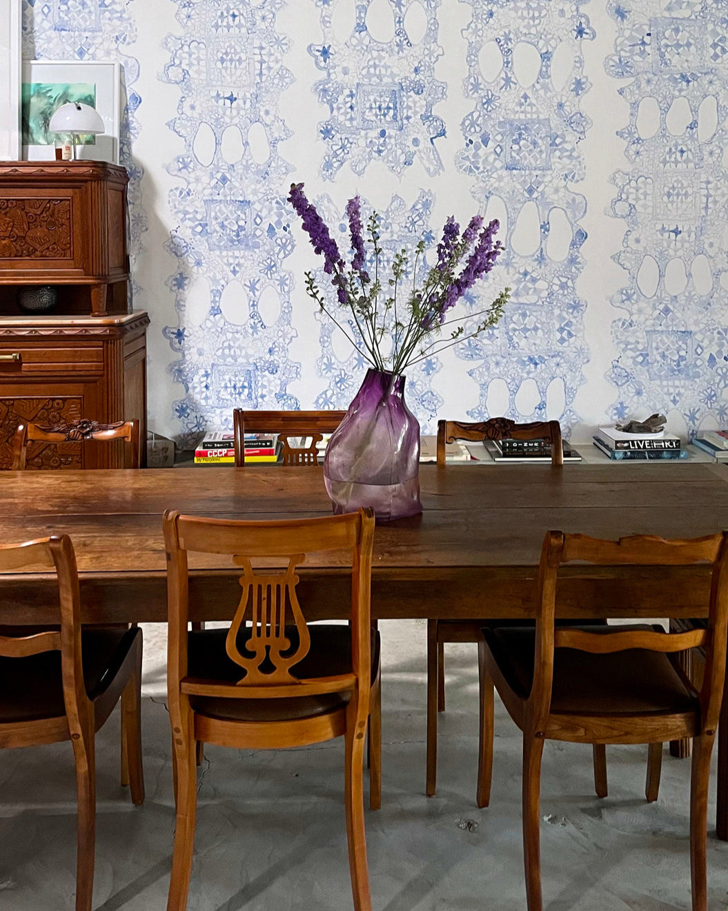 Dining room with wooden table and chairs against a decorative wall.