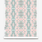 Partially unrolled wallpaper yardage in a painterly gometric stripe in gray, blue and green on a pink field.