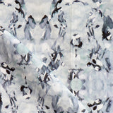 Detail of fabric in an abstract paint blotch print in blue, gray and purple on a white field.