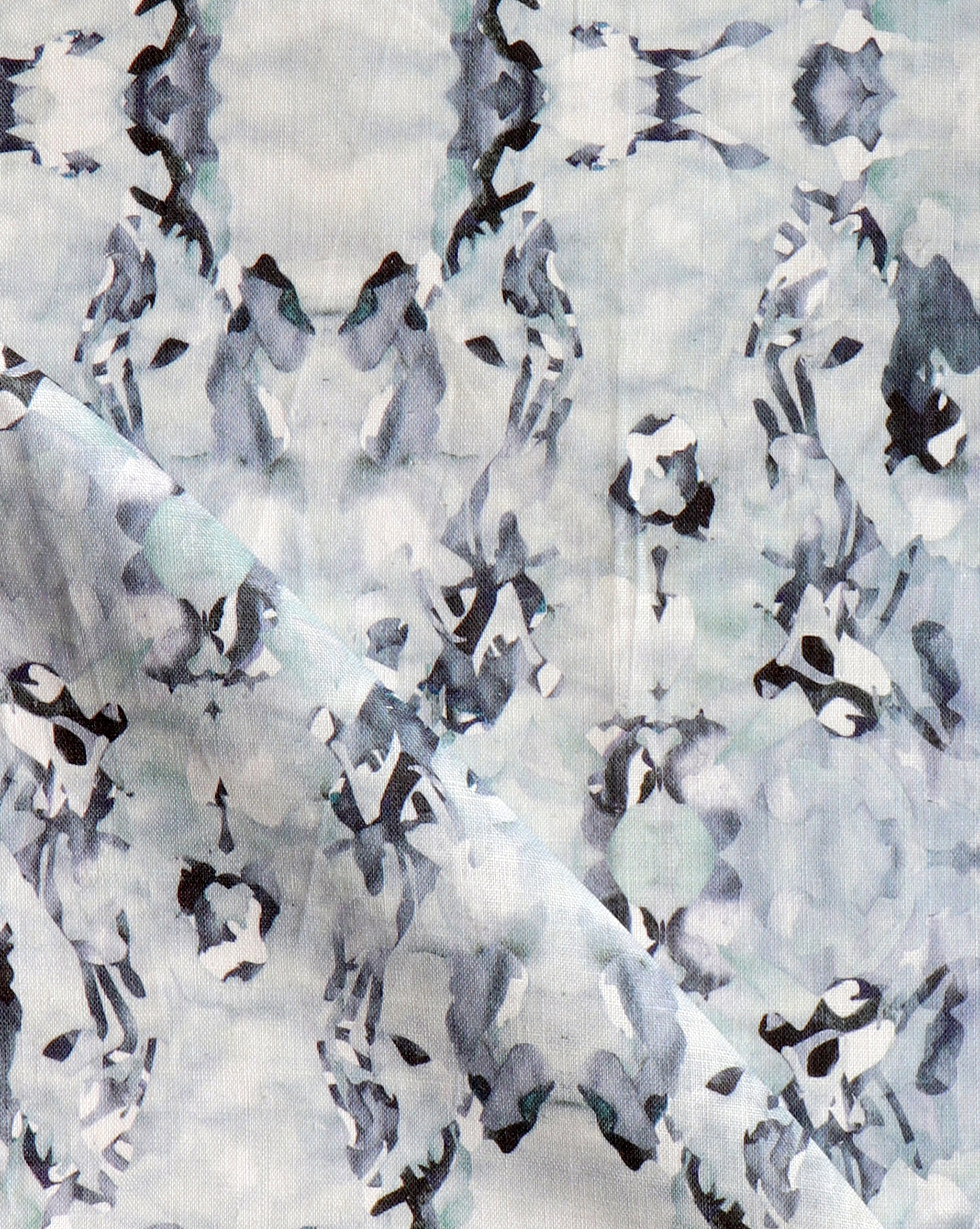 Detail of fabric in an abstract paint blotch print in blue, gray and purple on a white field.