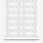 Partially unrolled wallpaper yardage in a striped ink blot print in shades of tan and purple on a cream field.