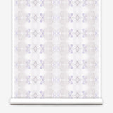 Partially unrolled wallpaper yardage in a striped ink blot print in shades of tan and purple on a cream field.