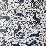 Detail of wallpaper in a deer, leaf and flower print in navy on a white field.