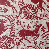 Close-up of wallpaper in a deer, leaf and flower print in red on a mottled beige field.