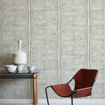 Modern brown chair and small table against a green geometric wallpaper