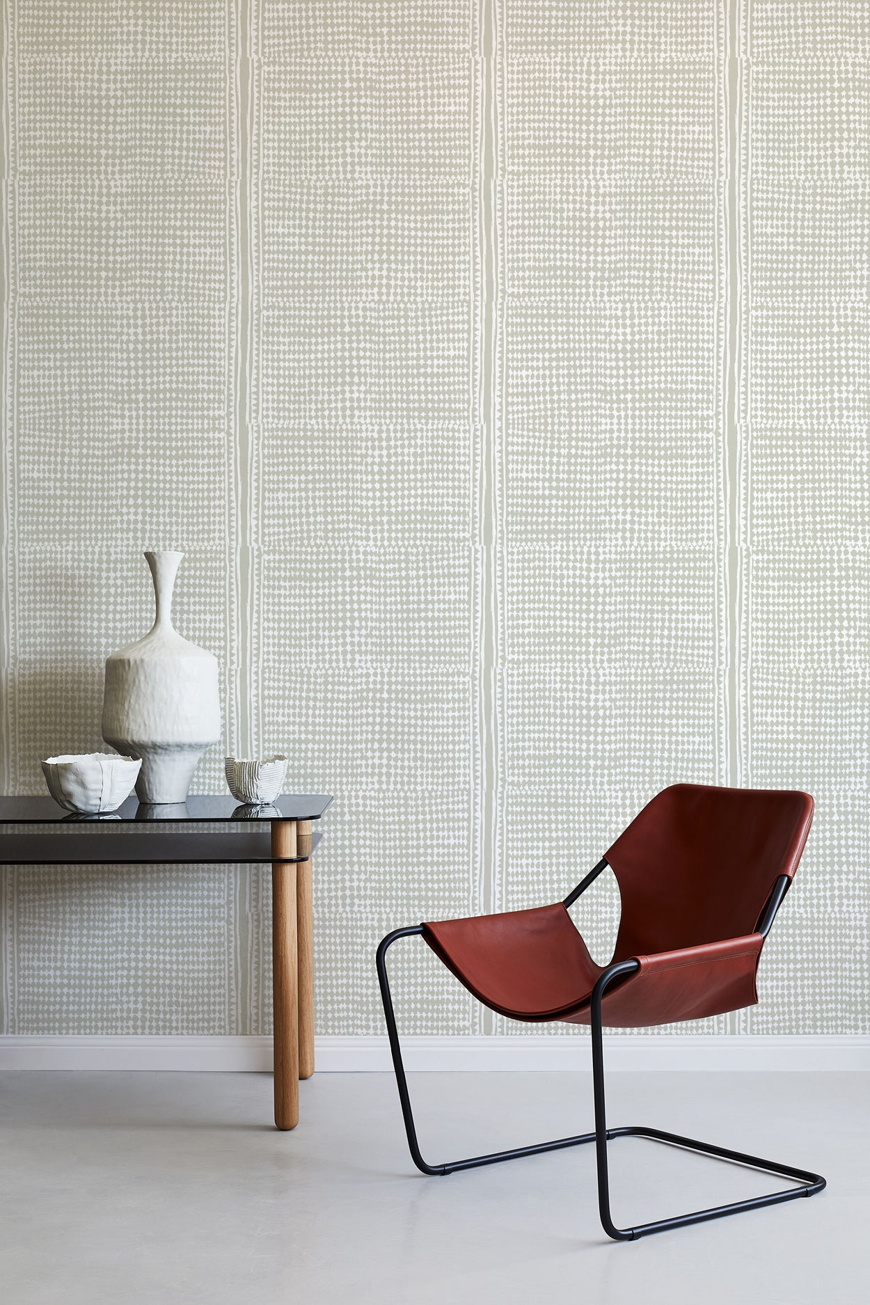 Brown chair and small table against a grey geometric wallpaper