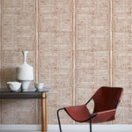 Modern brown chair with black frame against a brown geometric wallpaper