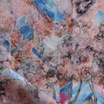 Detail of fabric in a painterly botanical print in pink, orange, gray and blue.