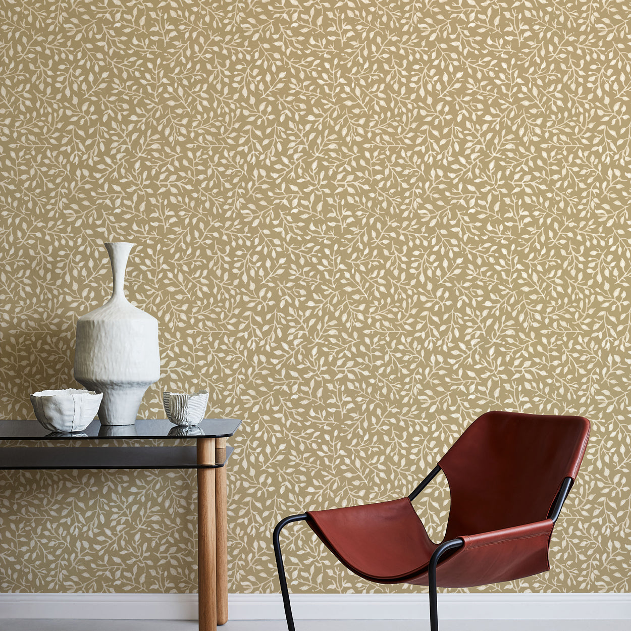 Modern interior with a red chair, table, and decorative items against a leaf patterned wall.
