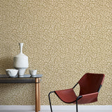 Modern interior with a red chair, table, and decorative items against a leaf patterned wall.