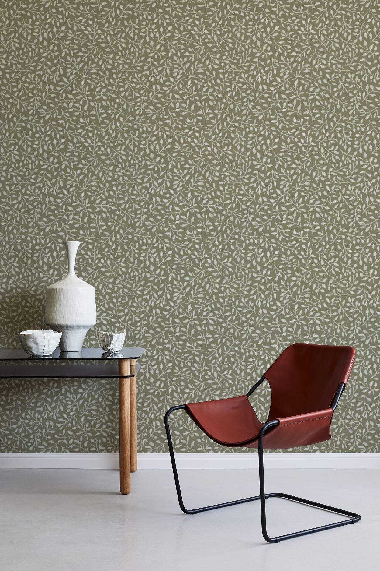 Modern red chair and table against a patterned green wall