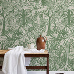 A bench with a towel and clay vases stands in front of a wall papered in a playful jungle print in green and cream.