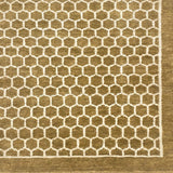 Handknotted rug sample in a small scale hex lattice in cream on an ochre field with a border at the right and bottom. 