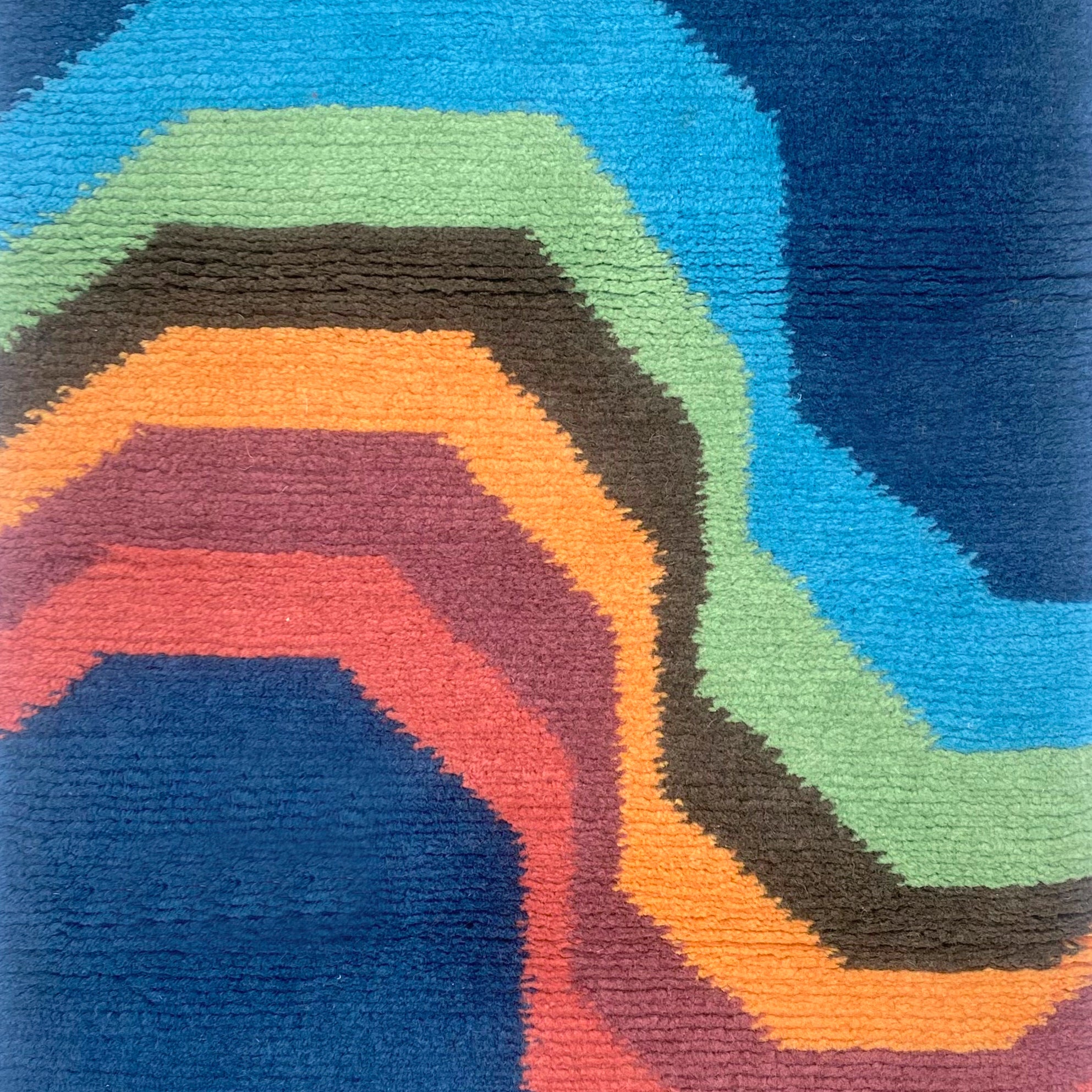 Handknotted carpet with a retro rainbow stripe on a blue field. 