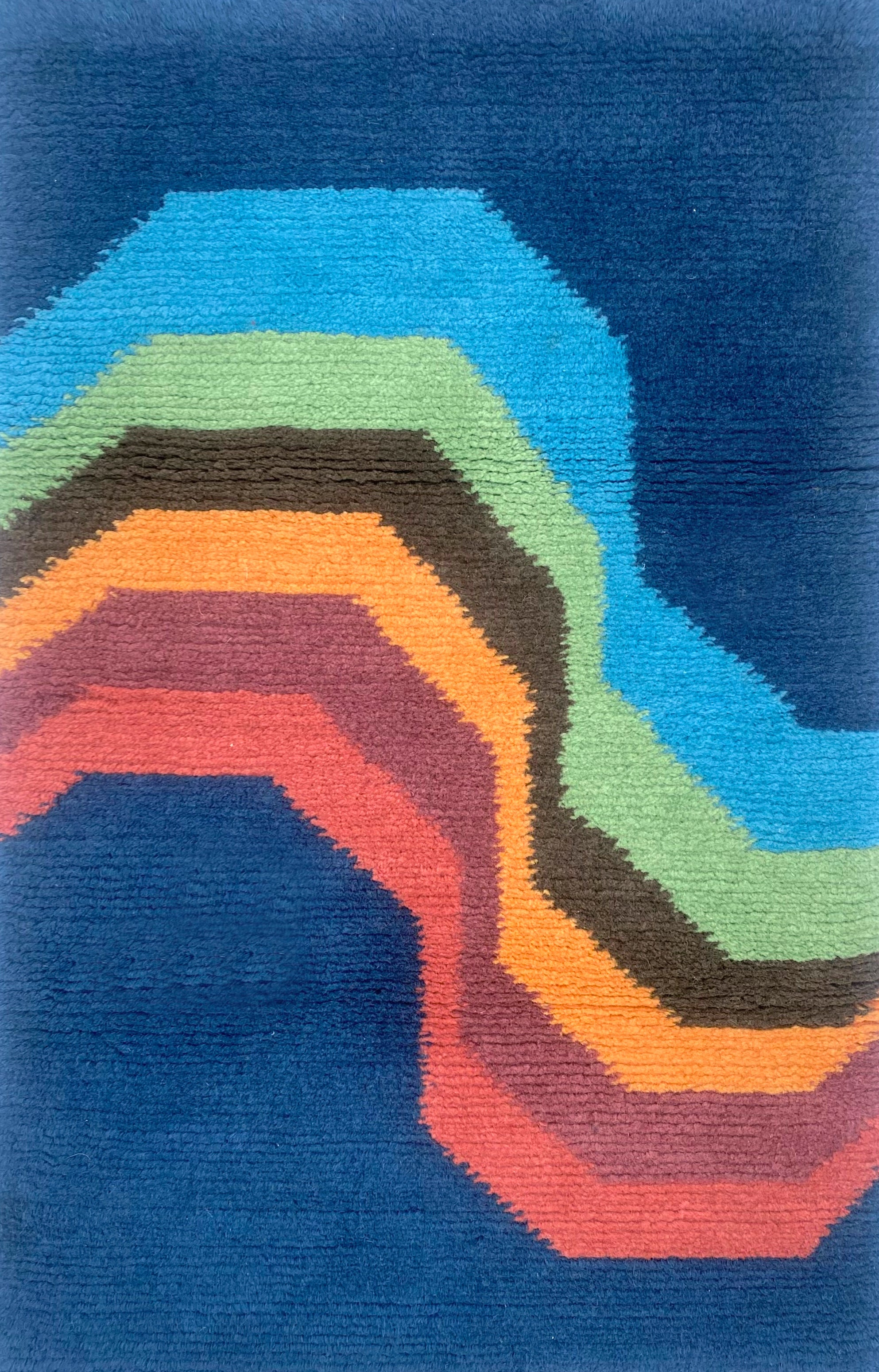 Handknotted carpet with a retro rainbow stripe on a blue field. 