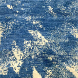 Handknotted rug sample in an abstract texture in blue with accents of cream. 
