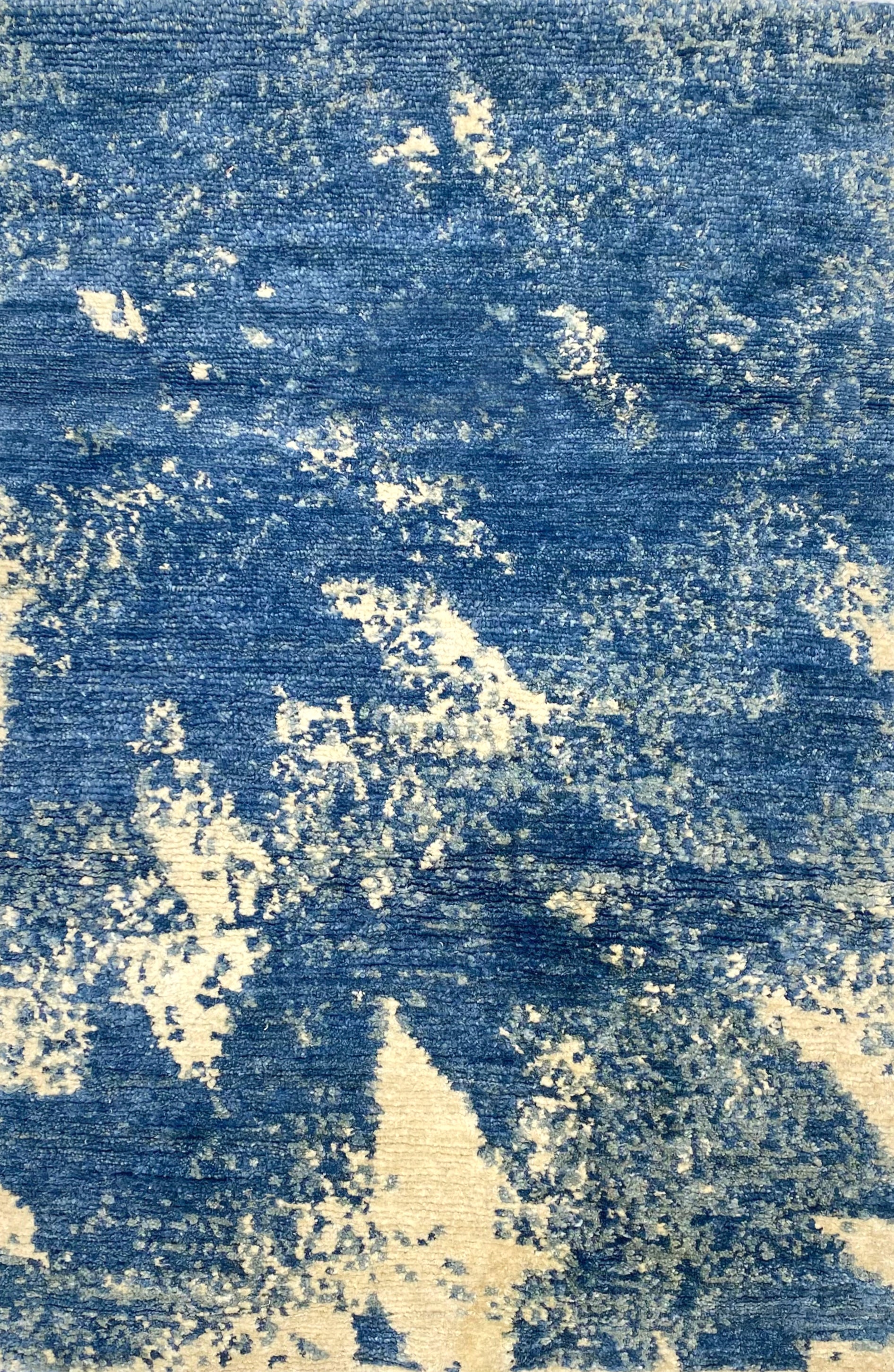 Handknotted rug sample in an abstract texture in blue with accents of cream. 