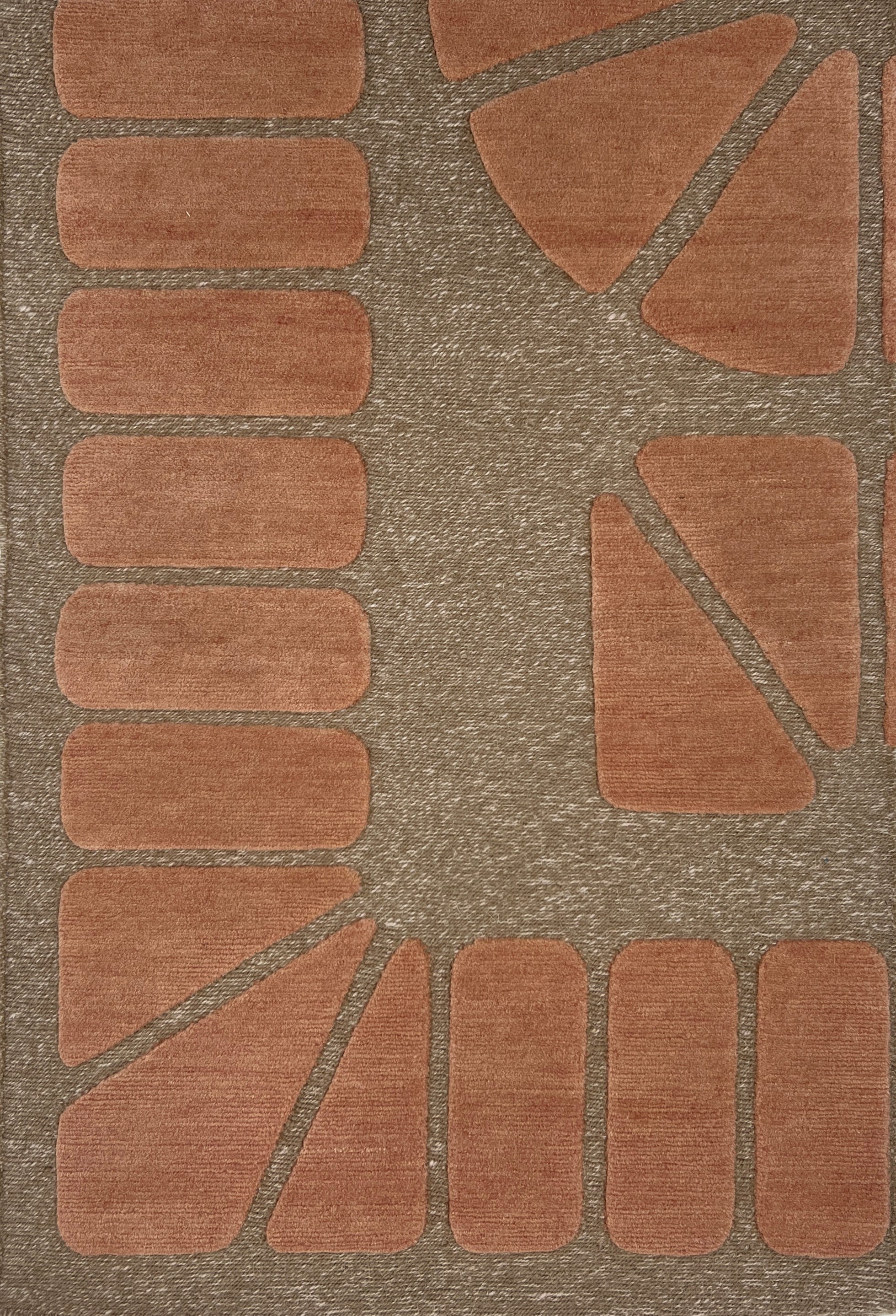 Handknotted carpet in a raised geometric design in peach on a taupe field.