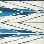 Handknotted rug sample in a modern herringbone design in shades of blue ona. white field. 