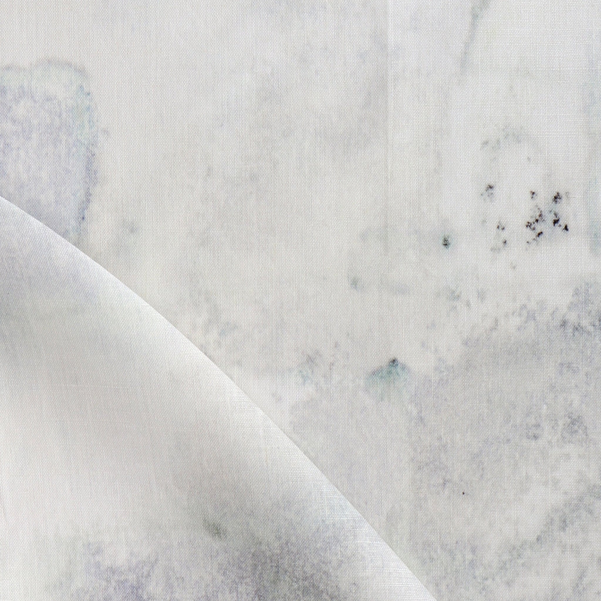 Detail of fabric in a minimal splatter print in shades of gray on a cream field.