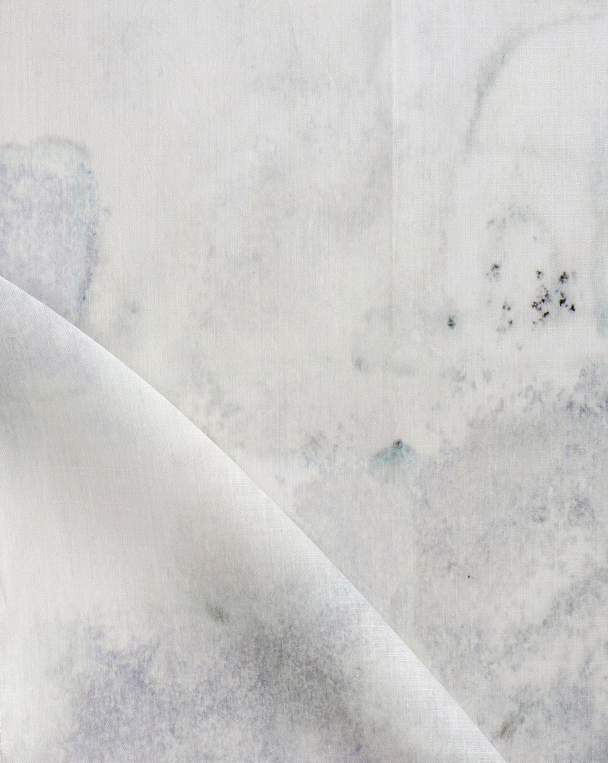 Detail of fabric in a minimal splatter print in shades of gray on a cream field.