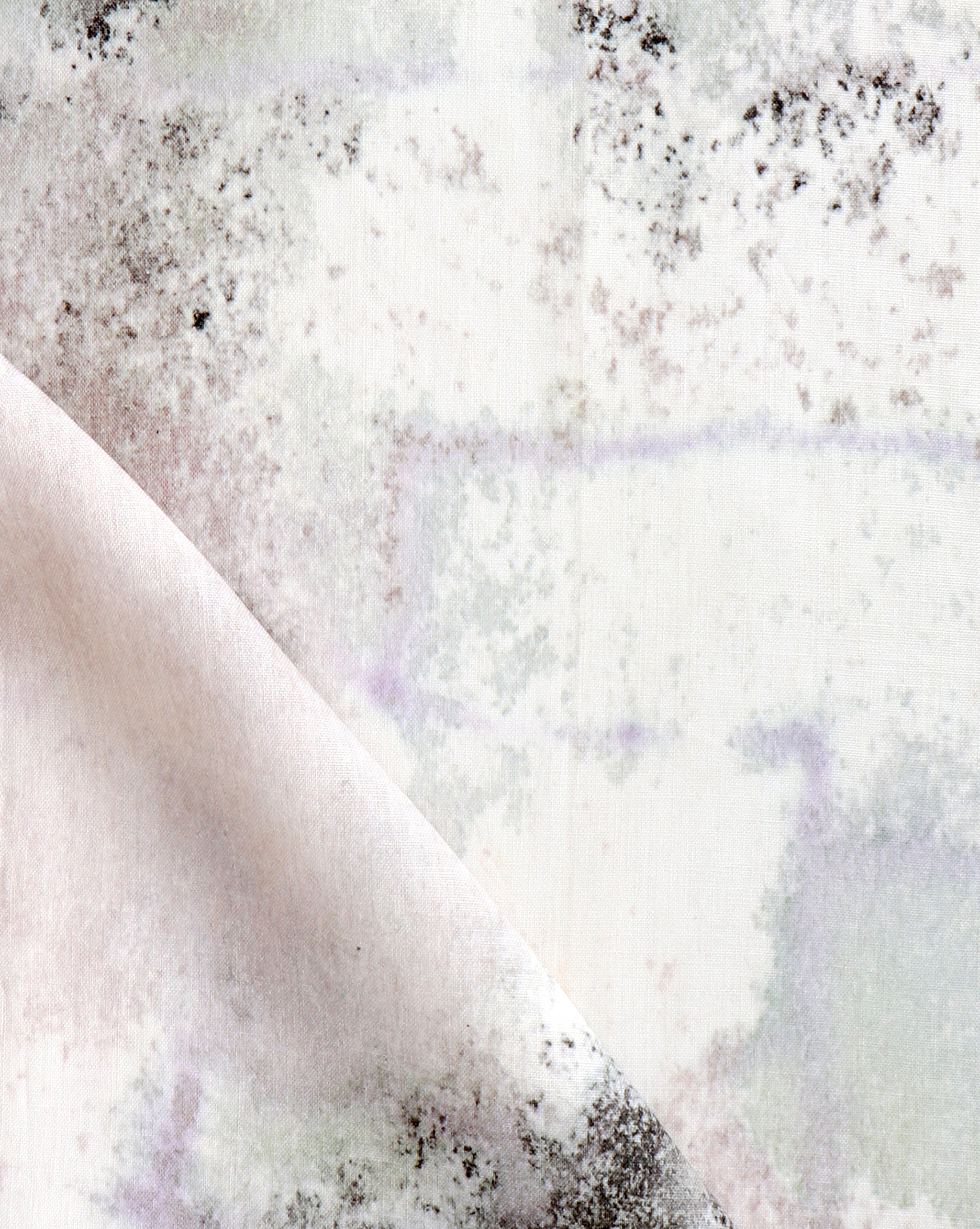 Detail of fabric in a minimal splatter print in shades of gray and pink on a cream field.