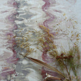 Flowers and branches lie on top of fabric yardage in an abstract paint blot pattern in shades of cream, gray and pink.