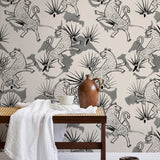 A bench with a towel and clay vases stands in front of a wall papered in a leopard and leaf print in gray and cream.