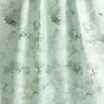 Draped fabric yardage in a dense photorealistic floral print in shades of gray and pastel green.