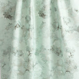 Draped fabric yardage in a dense photorealistic floral print in shades of gray and pastel green.