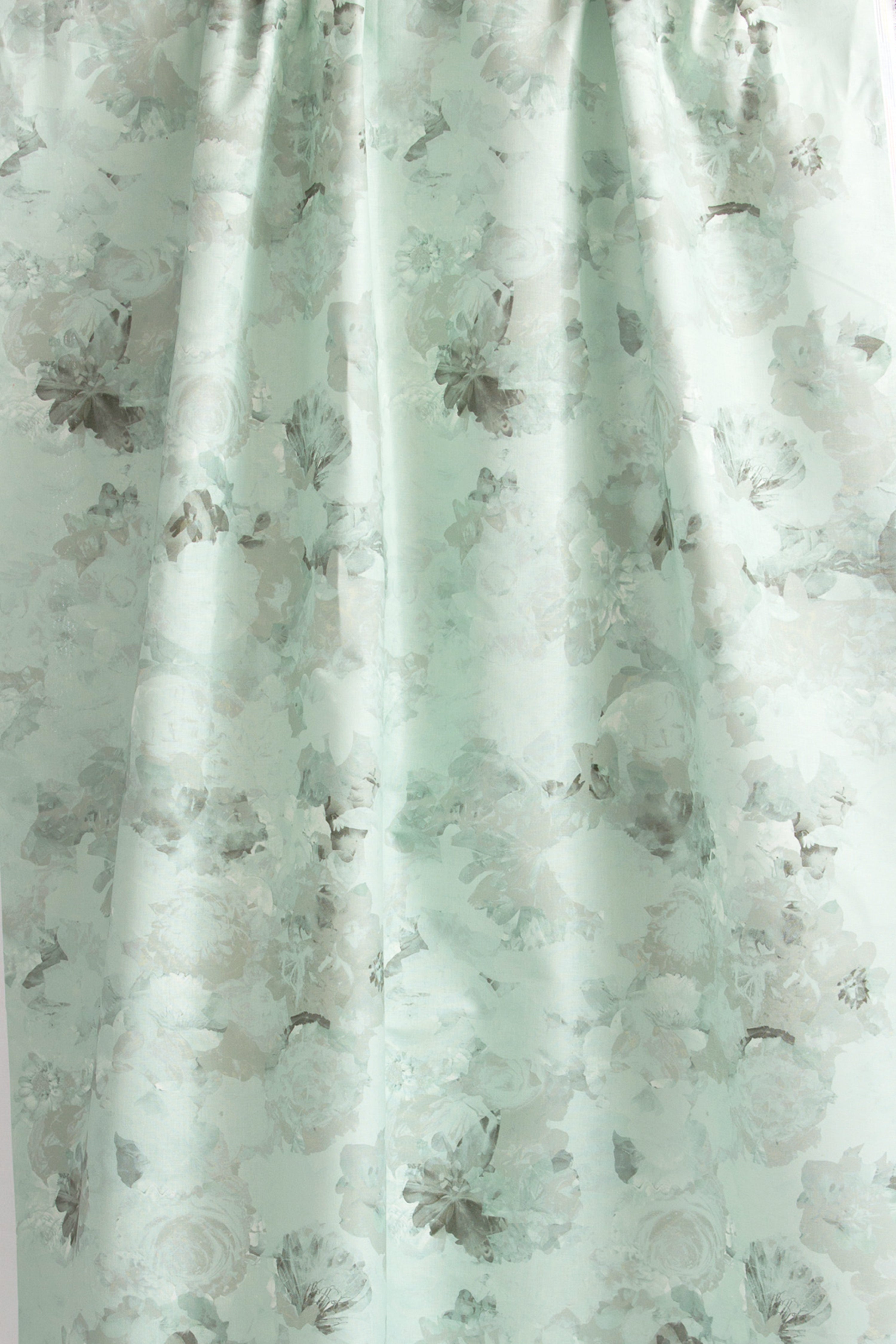 Draped fabric yardage in a dense photorealistic floral print in shades of gray and pastel green.