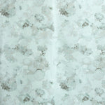 Detail of fabric in a dense photorealistic floral print in shades of gray and pastel green.