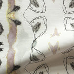 Detail of draped fabric yardage in an abstract ikat stripe print in shades of gray, pink and yellow on a white field.