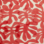 Detail of fabric in a playful repeating leaf print in shades of red on a cream field.