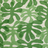 Detail of fabric in a playful repeating leaf print in shades of green on a cream field.